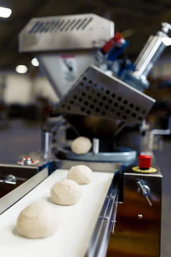 Industrial dough dividers and rounders produce dough balls on conveyor belts in Munster, IN.